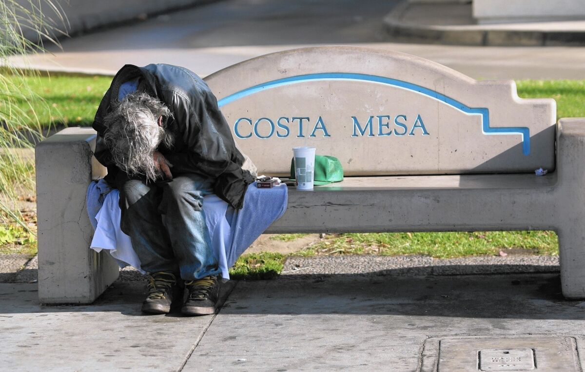 A homeless man sleeps on a bench near Wilson Street and Harbor Boulevard in Costa Mesa. According to a Vanguard University survey, Costa Mesa’s homeless population increased 45% between fall 2013 and fall 2015.