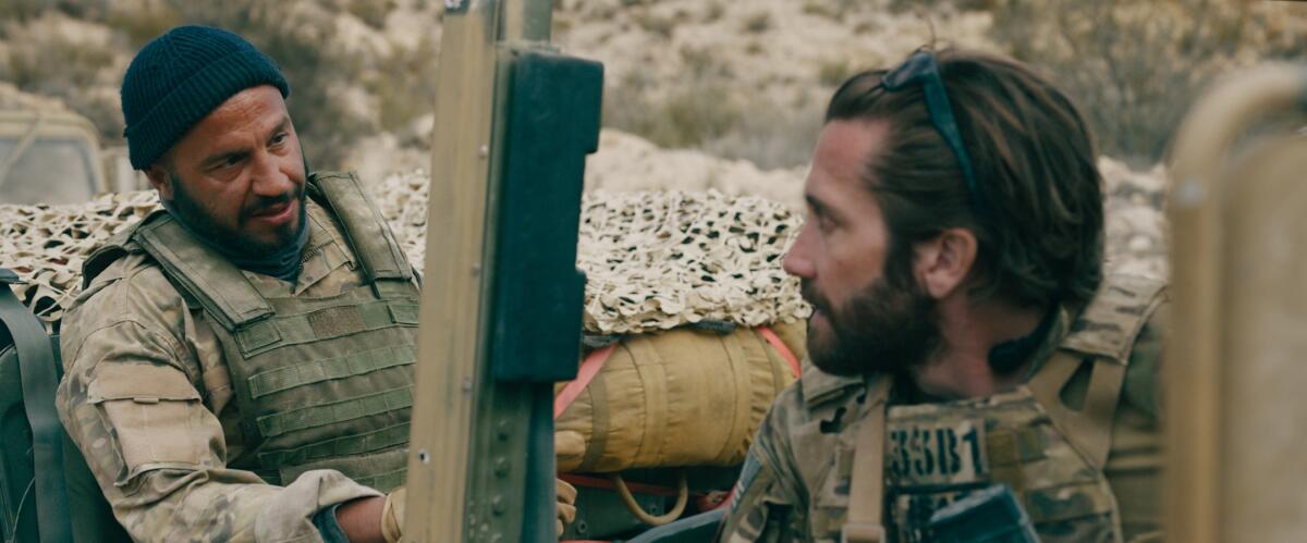 two soldiers talk to each other as they sit in the back of a truck 