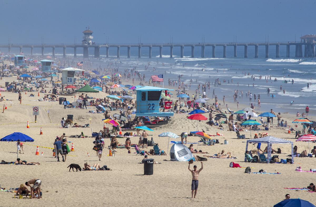 Thousands of beachgoers enjoy a warm, sunny day in Huntington Beach amid California's stay-at-home restrictions.