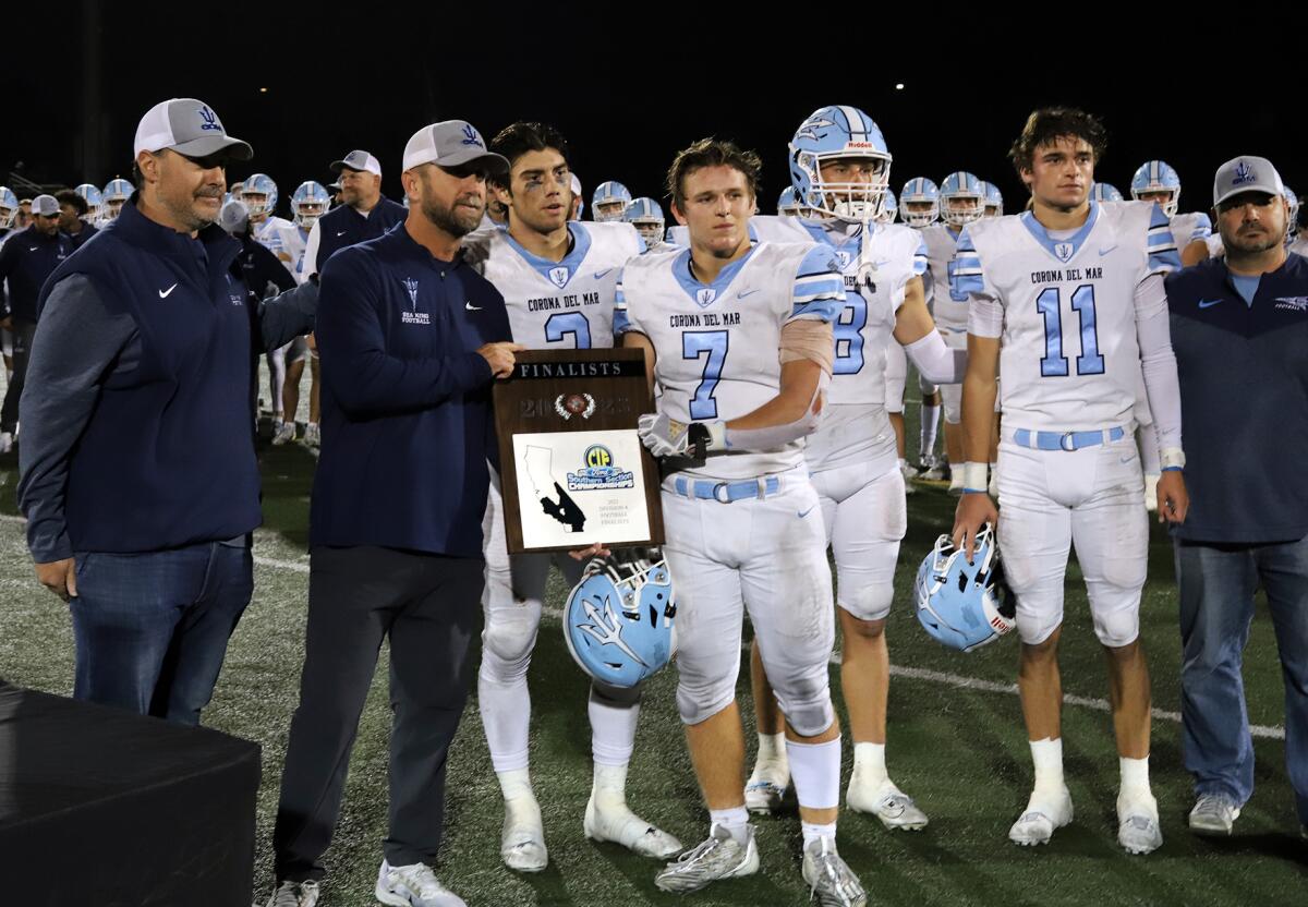Corona del Mar football head coach Kevin Hettig and CdM's captains pose for a picture with the runner-up CIF plaque.