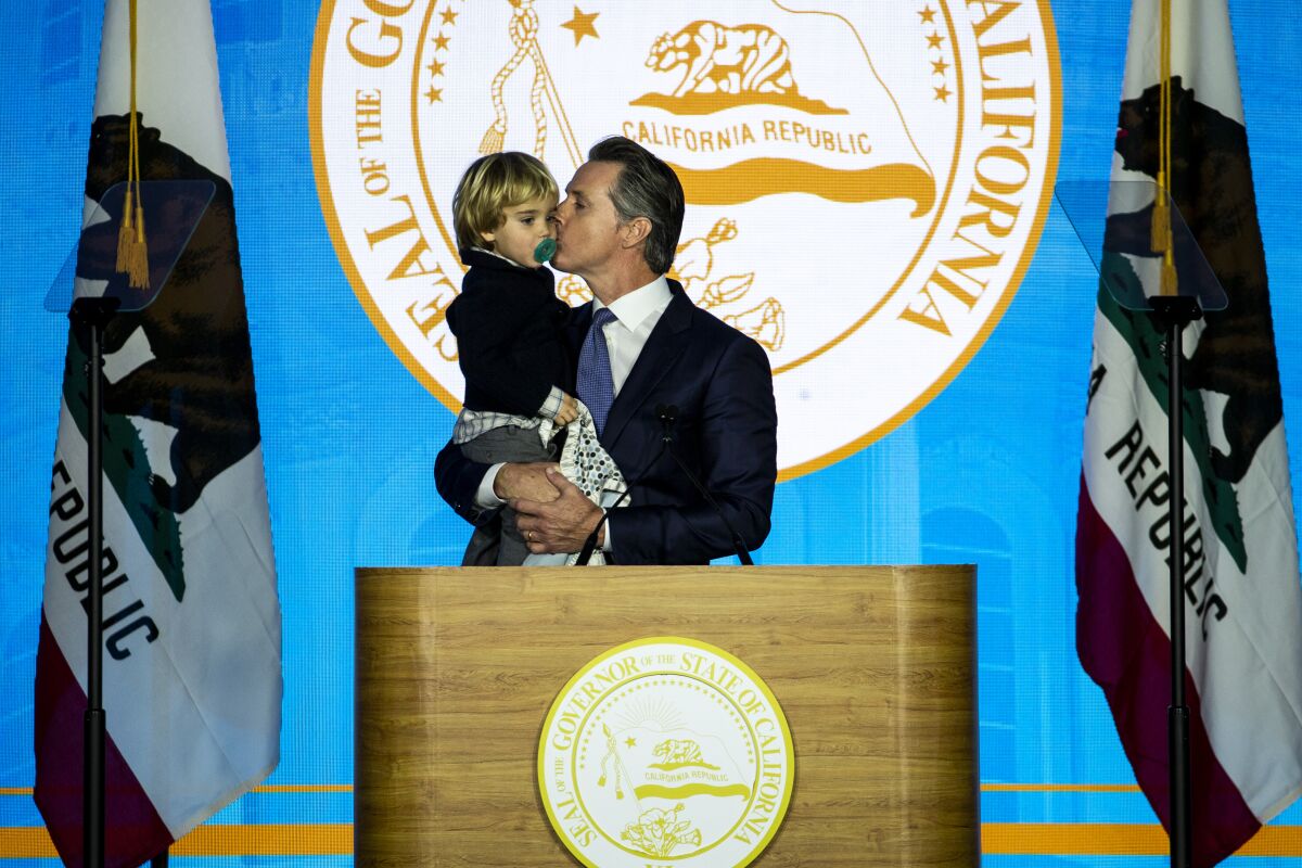 Gov. Gavin Newsom kisses his son Dutch on a stage
