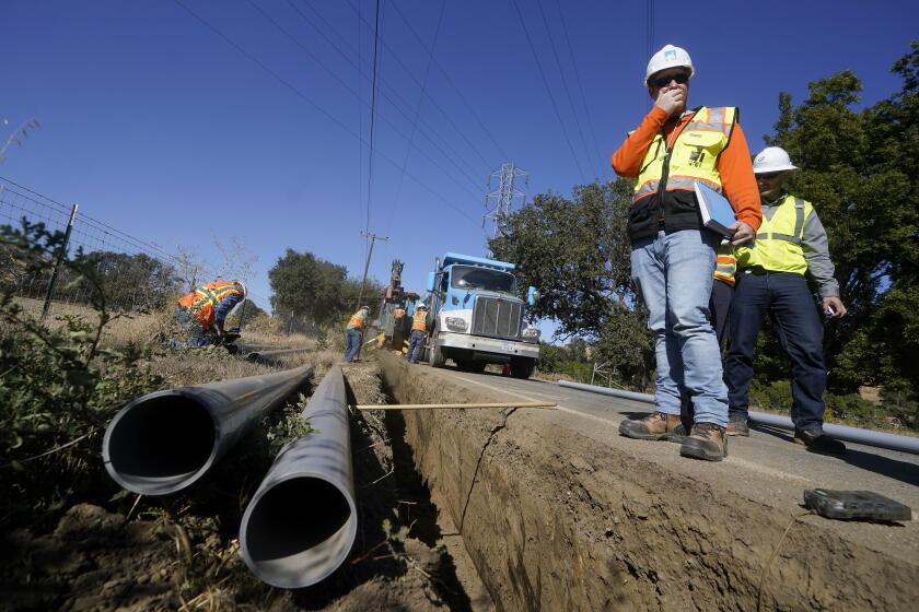 FILE - Paul Standen, senior director of underground regional delivery, second from right, and project manager Jeremy Schanaker, right, look on during a tour of a Pacific Gas and Electric crew burying power lines in Vacaville, Calif., Wednesday, Oct. 11, 2023. On Thursday, Nov. 16, 2023, the California Public Utilities Commission approved a plan for PG&E to bury 1,230 miles of power lines to reduce the risk of starting wildfires. The plan is a big part of an overall increase in rates that will raise utility bills by more than $32 per month for the average customer. (AP Photo/Jeff Chiu, File)