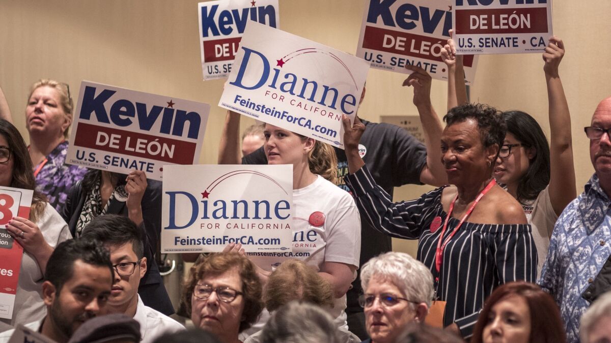 Supporters of Kevin de Leon and Dianne Feinstein hold signs during a meeting of the women's caucus at the Marriott Hotel in downtown Oakland.