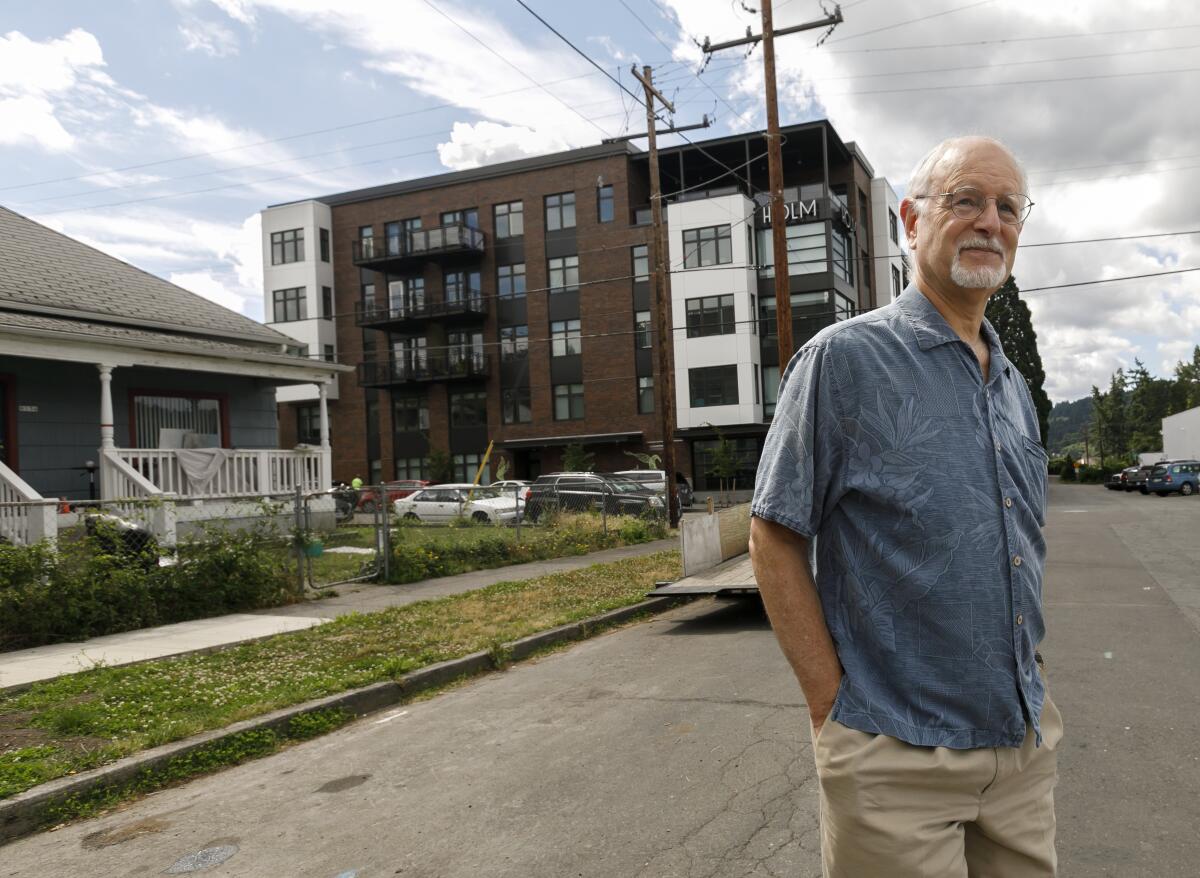 Rod Merrick, president of the Eastmoreland Neighborhood Assn., looks at a large complex in a southeast Portland, Ore., neighborhood, constructed next to a single family home in July.