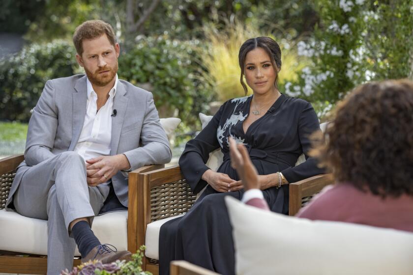 Prince Harry and Meghan Markle sit outside with Oprah Winfrey.