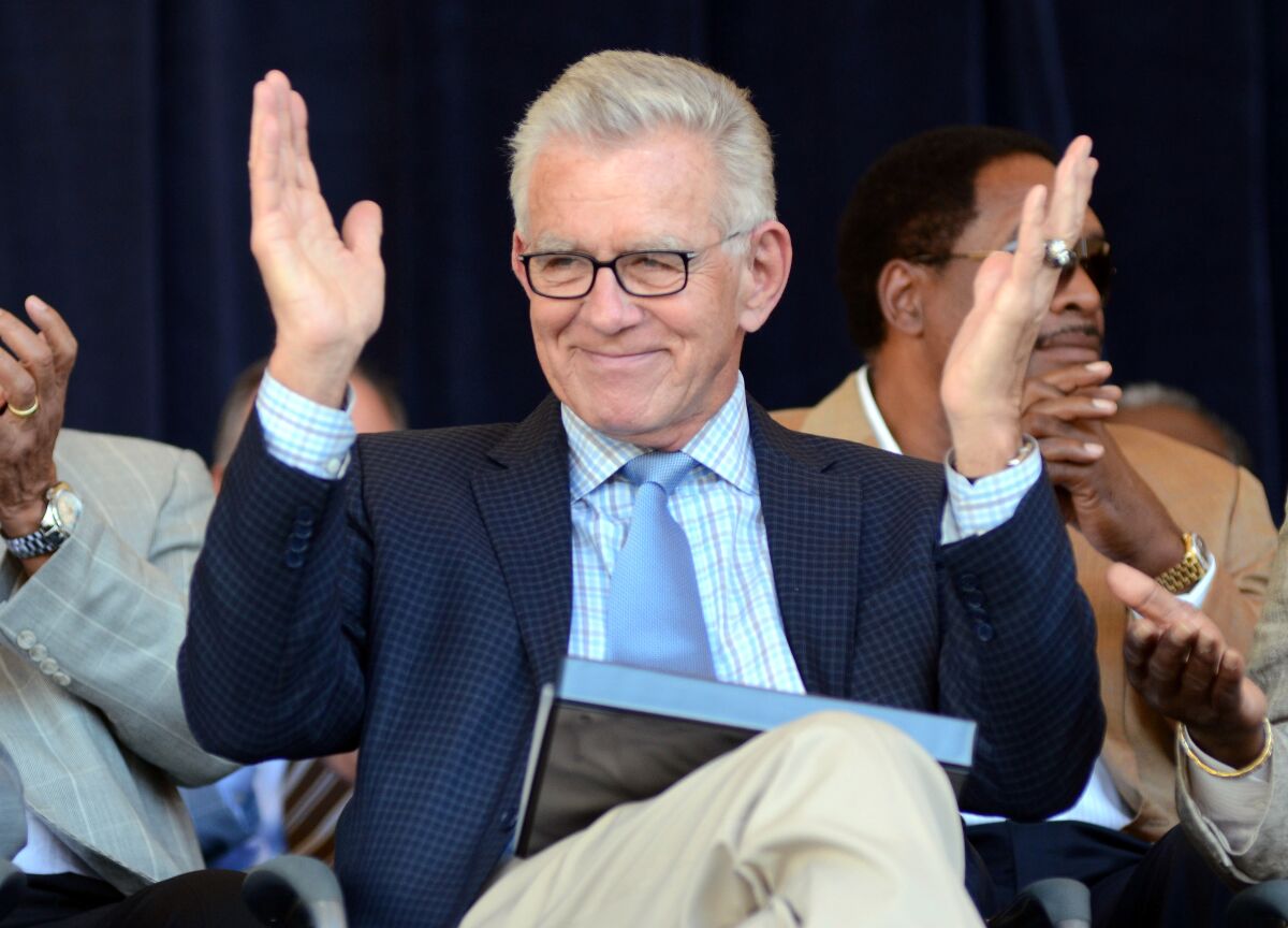 Tim McCarver holds his hands open and out while sitting.