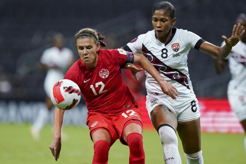 FILE - Canada's Christine Sinclair (12) and Trinidad and Tobago's Victoria Swift compete for the ball.