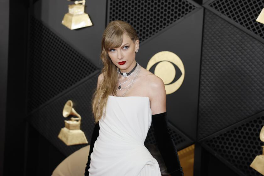 Taylor Swift in a strapless white gown with black gloves and jewelry posing against a black backdrop