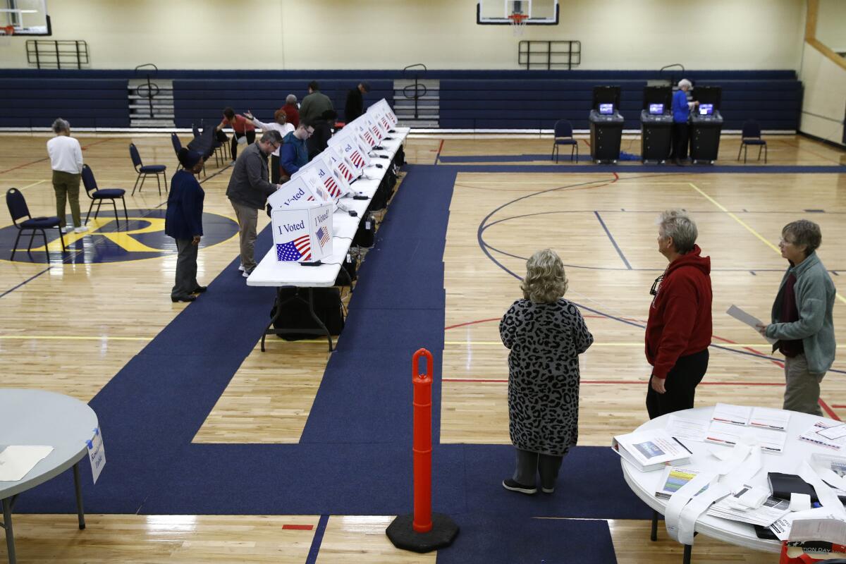Voters wait in line to cast ballots in a gym.