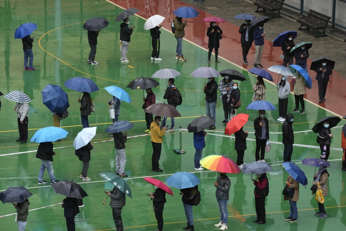 Residents lining up under their umbrellas for coronavirus tests