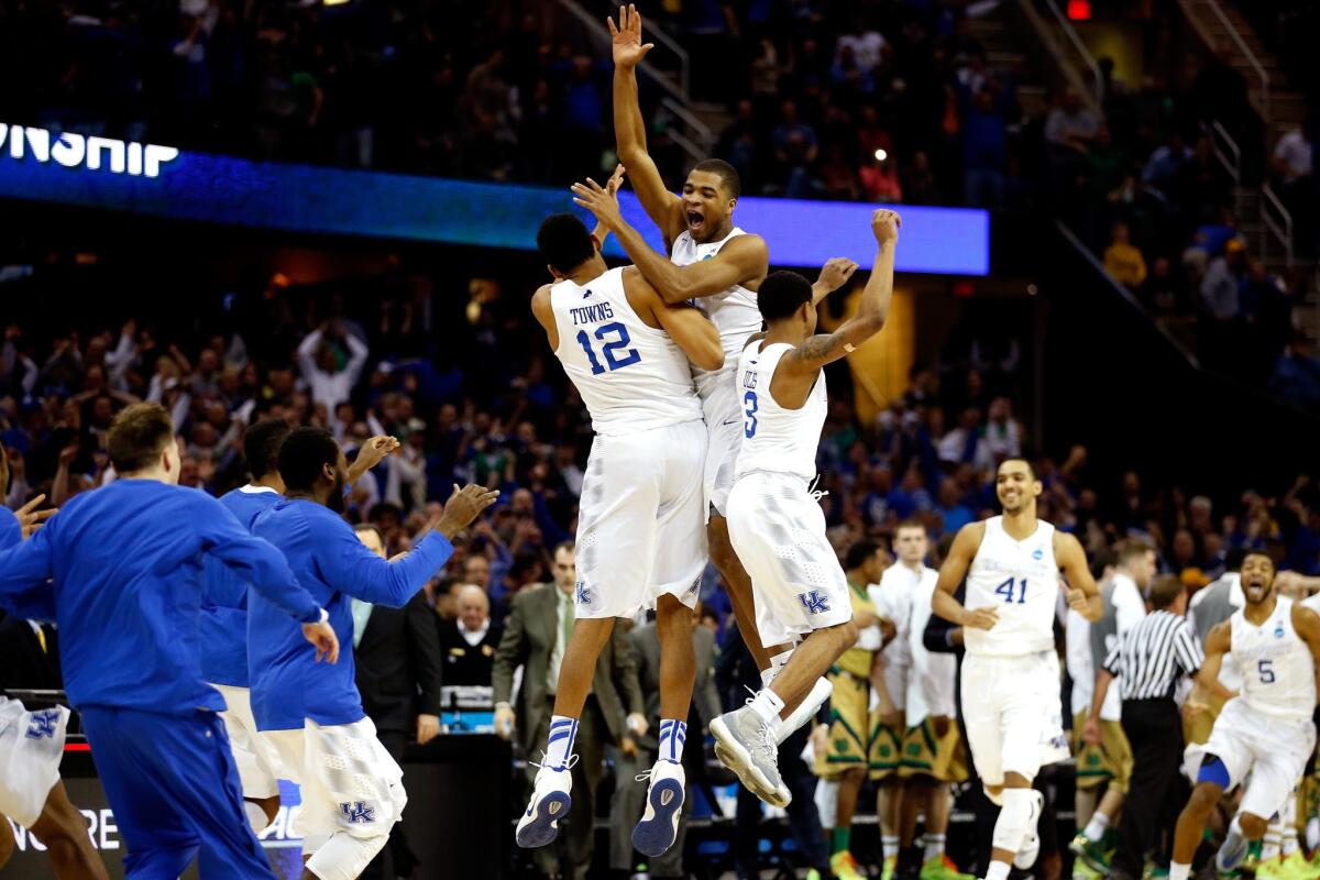 Kentucky guard Aaron Harrison leaps above teammates Karl-Anthony Towns (12) and Tyler Ulis (3) as they celebrate their 68-66 victory over Notre Dame in the NCAA Midwest Regional final on Saturday.