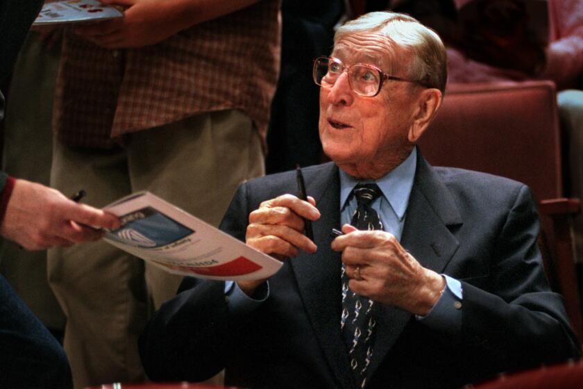John Wooden signs autographs between games during the Wooden Classic in Anaheim in 1999.