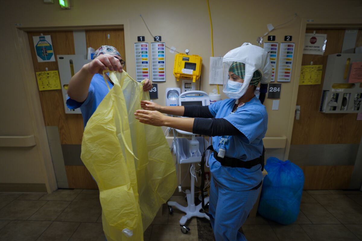 Nurses put on new gloves and gowns before entering a room with patient who has COVID-19.