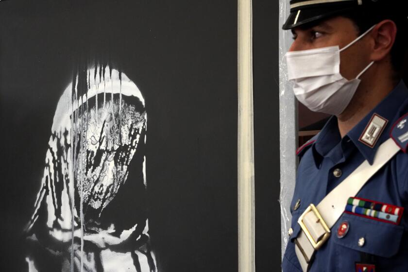 Italian authorities unveil a stolen artwork painted by the British artist Banksy as a tribute to the victims of the 2015 terror attacks at the Bataclan music hall in Paris, during a press conference in L' Aquila, Italy, Thursday June, 11, 2020 . The L’Aquila prosecutors office said the work was recovered on Wednesday during a search of a home in Tortoreto, a city near the Adriatic coast in the Abruzzo region’s Teramo province. (AP Photo/Andrea Rosa)