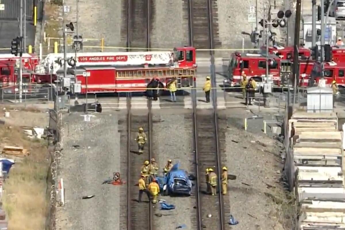 Two firetrucks sit on a railroad crossing as firefighters gather on the tracks.