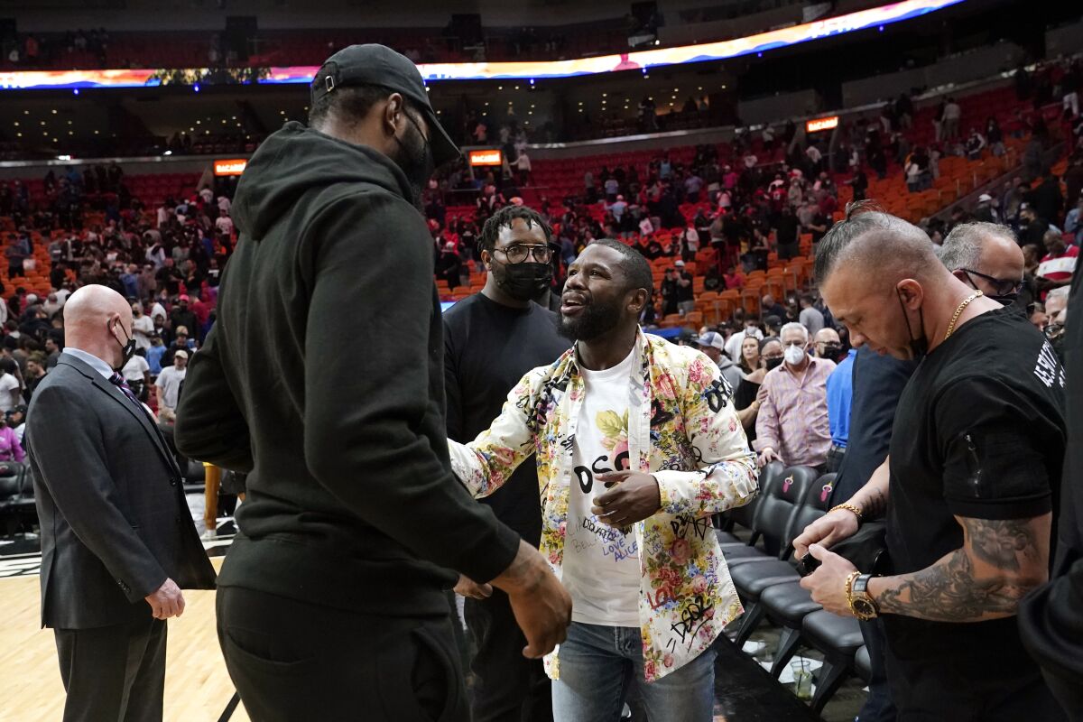 Former professional boxer Floyd Mayweather, center right, talks with Miami Heat forward Markieff Morris, center left, after an NBA basketball game between the Heat and Toronto Raptors, Monday, Jan. 17, 2022, in Miami. (AP Photo/Lynne Sladky)