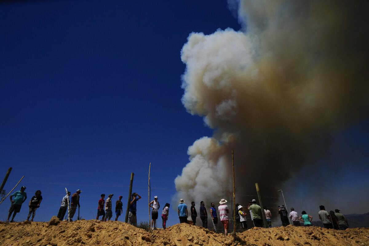 ARCHIVO - Residentes miran una columna de humo