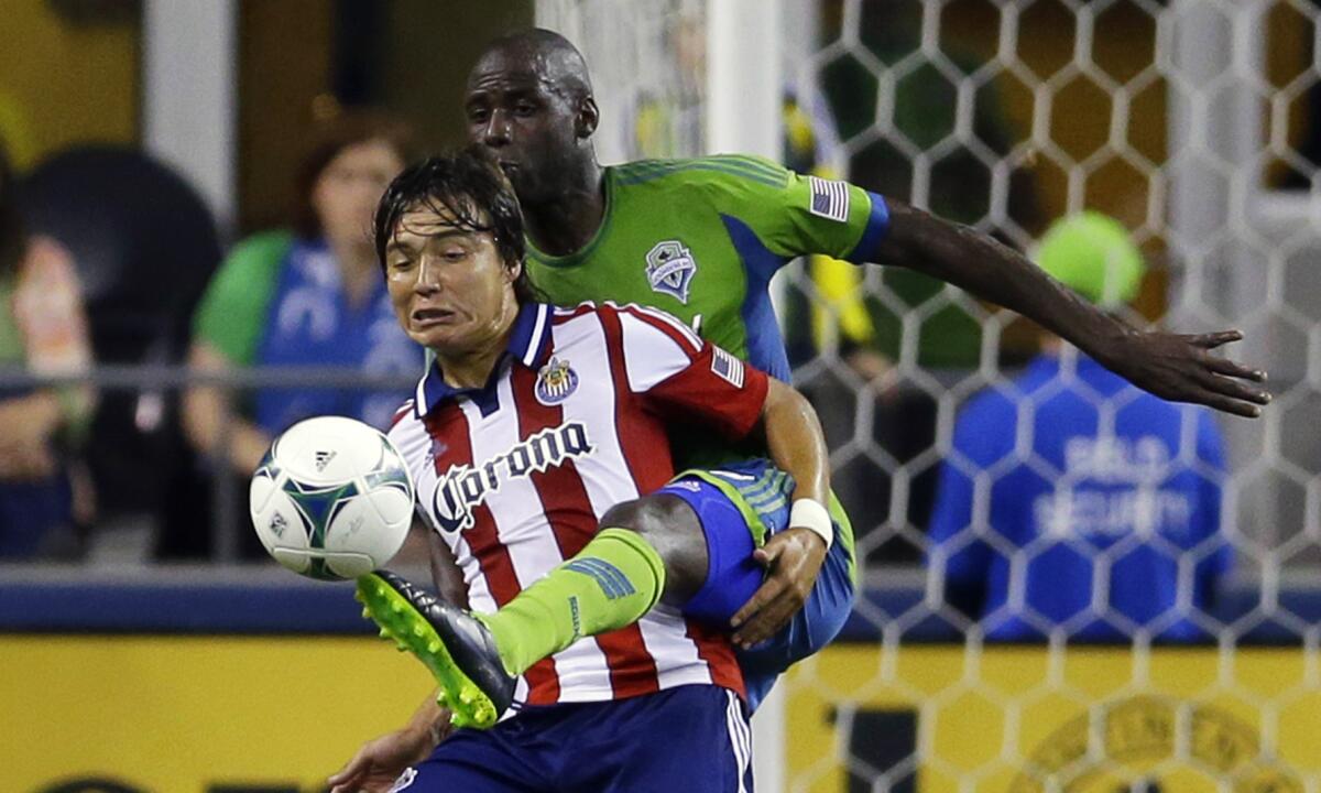 Seattle's Djimi Traore kicks the ball away from Chivas USA's Erick "Cubo" Torres during a game in September 2013.