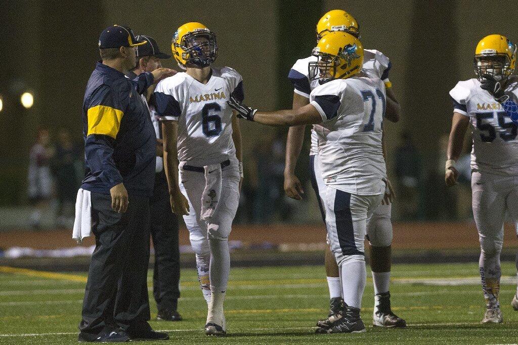 Marina High quarterback Ian Green (6) is slow to get up after getting tackled by two Westminster defenders.