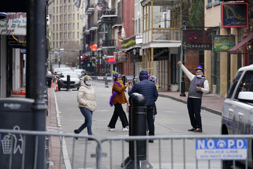 Tourists from Brooklyn take photos on a nearly deserted Bourbon Street during Mardi Gras in the French Quarter of New Orleans, Tuesday, Feb. 16, 2021. (AP Photo/Gerald Herbert)