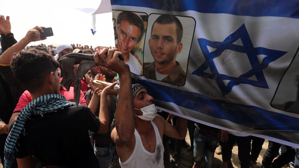 Palestinians carry a coffin covered with the Israeli flag and portraits of kidnapped Israeli soldiers during a protest near the Israeli border fence, east of Gaza City.