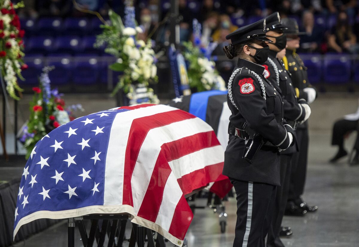 A police honor guard presides over the caskets of Bridgewater College campus police officer John Painter and campus safety officer J.J. Jefferson during their funeral service at the Atlantic Union Bank Center in Harrisonburg, Va., Wednesday, Feb. 9, 2022. Two officers who were shot to death on the campus of a private college in Virginia were remembered as heroes by their families, friends, dignitaries and police officers from around the country. (Daniel Lin/Daily News-Record via AP, Pool)