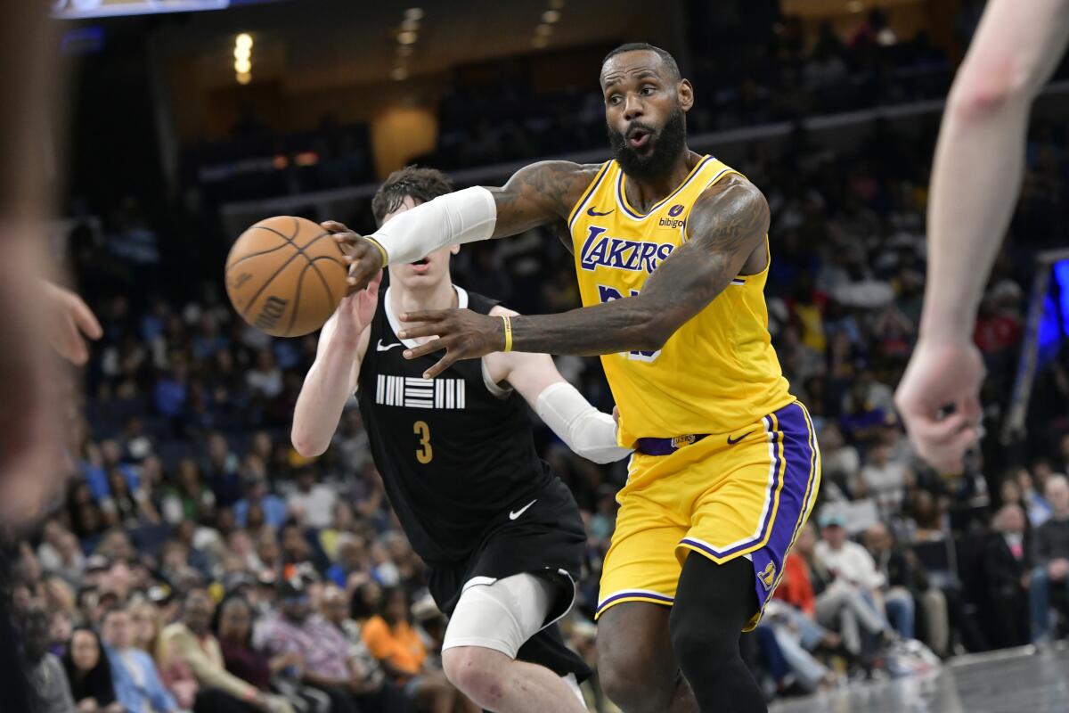 Lakers forward LeBron James passes the ball around Grizzlies forward Jake LaRavia on Friday night.