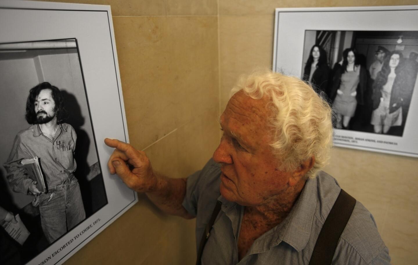 George Meyer, 86, a former Los Angeles County jailer, looks at a photograph showing cult leader Charles Manson being escorted to court at the Hall of Justice in 1971. Meyer, who attended today's reopening of the Hall of Justice, said he remembers securing Manson after his many court appearances.