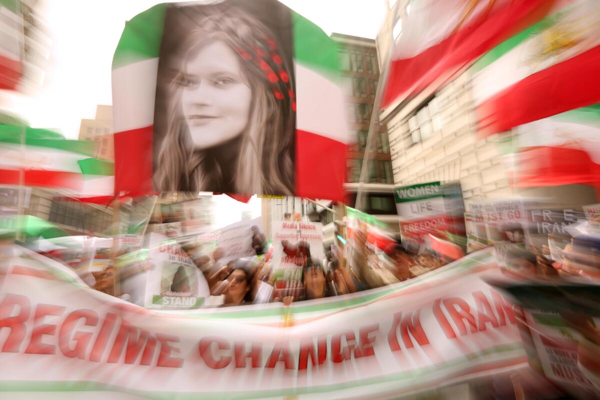 A woman's face on a red, white and green flag above a banner reading "REGIME CHANGE IN IRAN"