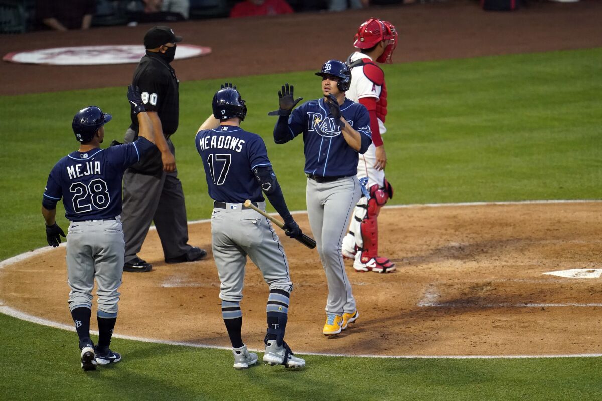 Tampa Bay Rays' Willy Adames, center right, is high-fived by Austin Meadows (17) after Adames scored on a single by Mike Brosseau during the third inning of a baseball game against the Los Angeles Angels Monday, May 3, 2021, in Anaheim, Calif. (AP Photo/Marcio Jose Sanchez)