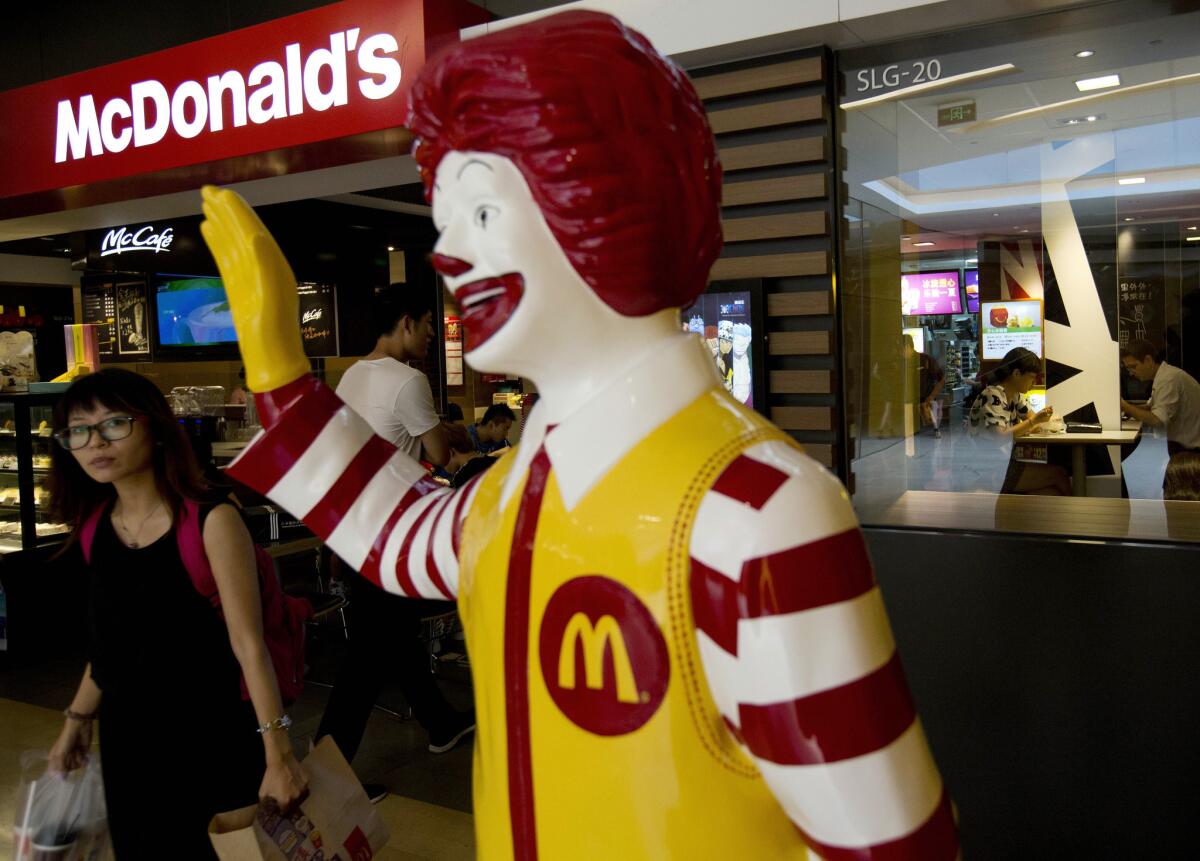 A Chinese customer walks past a statue of Ronald McDonald on display outside a restaurant in Beijing, China, as McDonald's tries to rebuild its reputation amid a meat scandal.