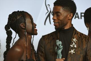 Lupita Nyong'o, left, and Chadwick Boseman look at each other while holding their SAG Awards in 2019