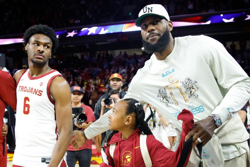 Lakers' LeBron James, right, pats the back of USC Trojans guard Bronny James (6) before the game