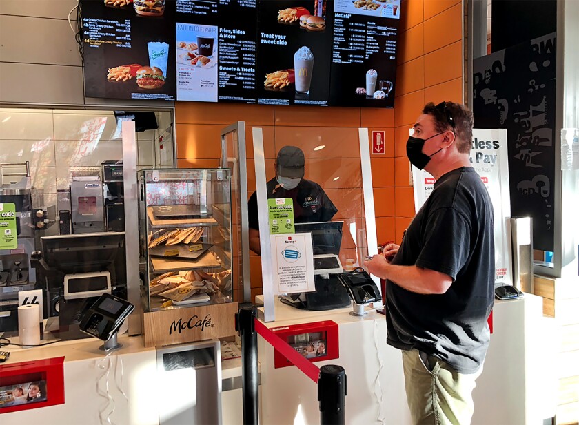 A man stands at an order window at a fast-food restaurant. 