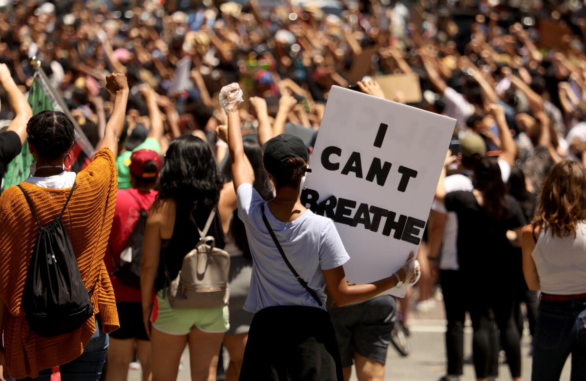 Hundreds of people, many raising a fist, attend a Black Lives Matter memorial service in 2020