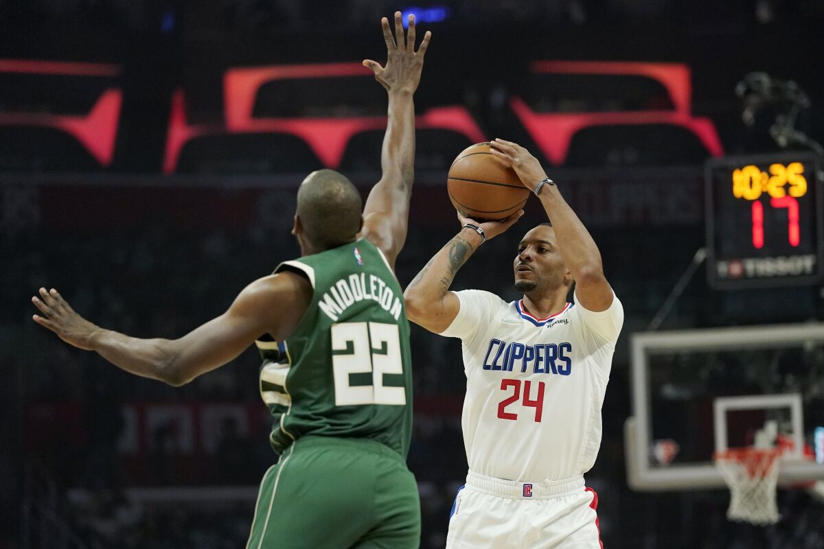 Los Angeles Clippers forward Norman Powell, right, shoots as Milwaukee Bucks forward Khris Middleton.