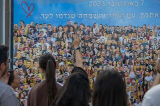 Visitors point to images of individuals in a photo of a large crowd of people