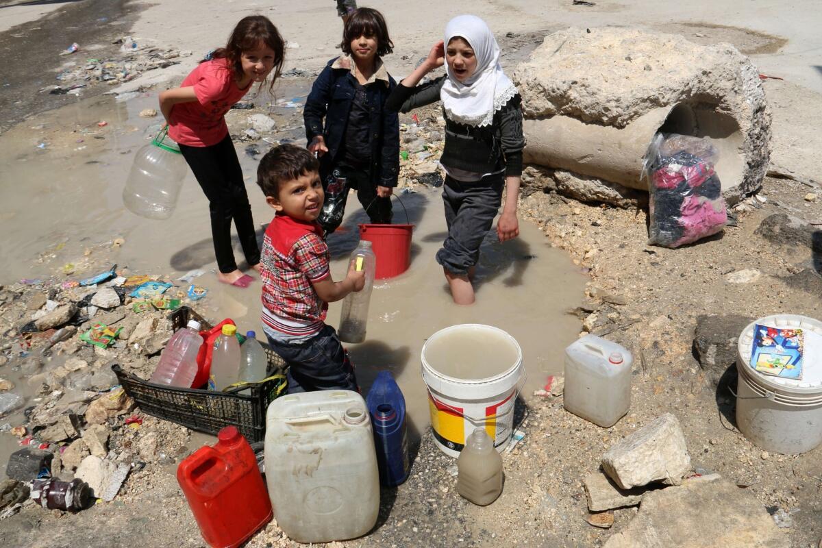 Syrian children collect water from the side of a road in the northern Syria city of Aleppo.
