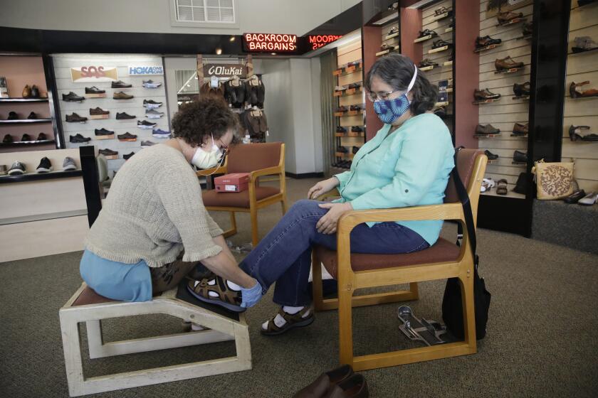 Yvonne Wright, right, shops for shoes with the help of sales person Jennifer Blythe-Freiner at Brown's Shoe Fit Co., Wednesday, May 20, 2020, in Visalia, Calif. Tulare County's board of supervisors voted 3-2 Tuesday to move further into the state's four-stage reopening plan than is allowed. That means nearly all businesses and churches could reopen, though county officials said businesses should adhere to state guidelines on social distancing and other health measures. (AP Photo/Marcio Jose Sanchez)