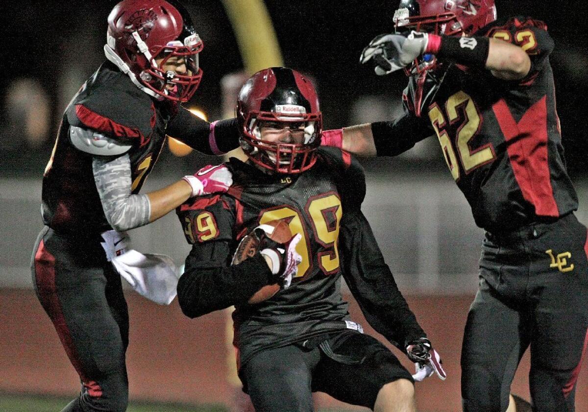 La Cañada's Theo Chamberlain celebrates with David Yoon and Graham Massimino after scoring a touchdown on Thursday.