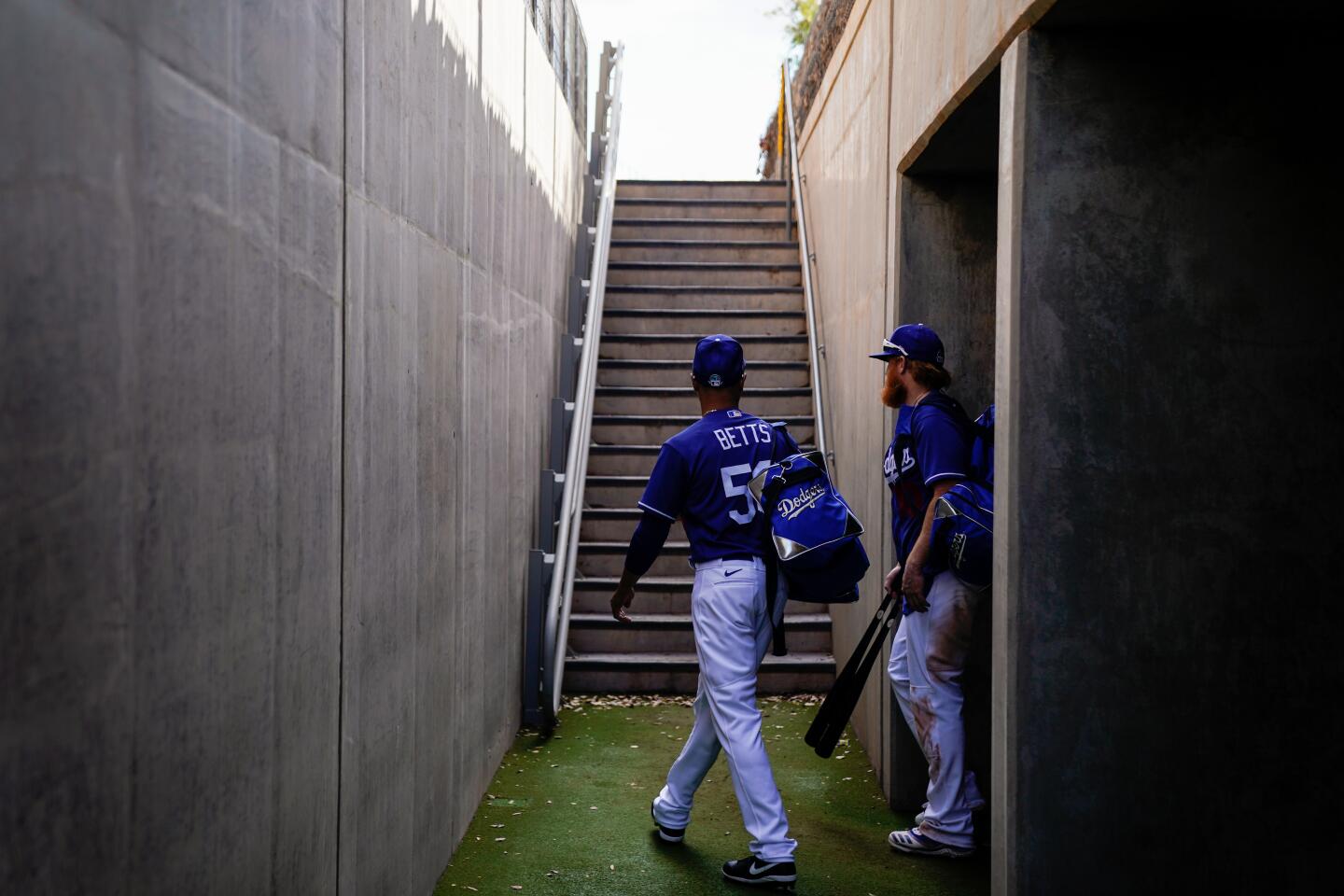 Dodgers right fielder Mookie Betts, left, and third baseman Justin Turner walk out of the tunnel after exiting an exhibition game against the Chicago Cubs in the top of the fifth inning at Camelback Ranch on Feb. 23, 2020.