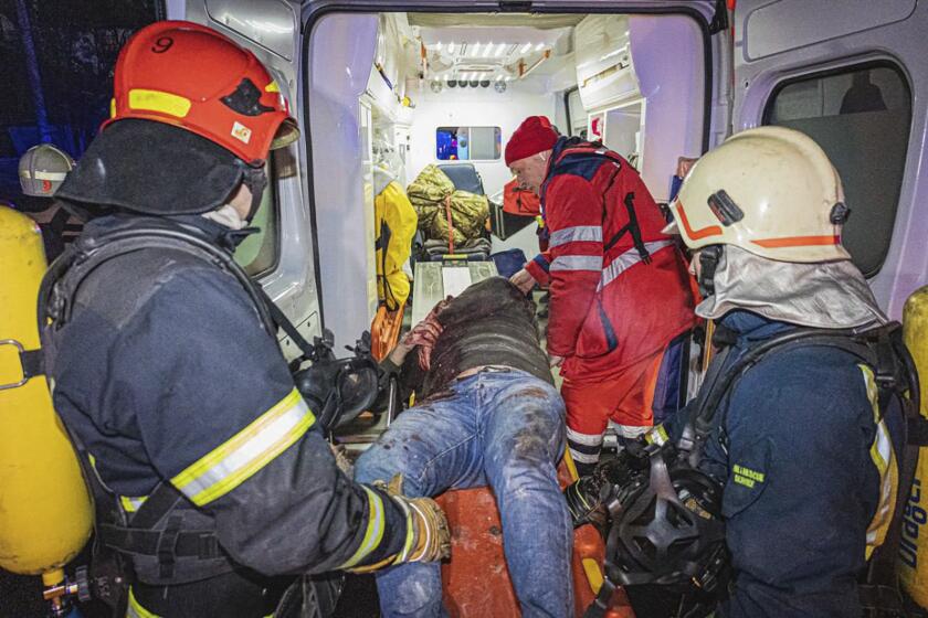 In this photo provided by the Ukrainian Emergency Service, firefighters and paramedics give the first aid to a man wounded in Russia's missile attack that hit a hotel in Kharkiv, Ukraine, late Wednesday, Jan. 10, 2024. (Ukrainian Emergency Service via AP)