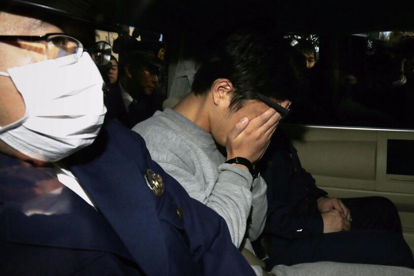 Suspect Takahiro Shiraishi (C) covers his face with his hands as he is transported to the prosecutor's office from a police station in Tokyo on November 1, 2017. The 27-year-old Japanese man, who was arrested after police found nine dismembered corpses rotting in his house, has confessed to killing all his victims over a two-month spree after contacting them via Twitter, media reports. / AFP PHOTO / JIJI PRESS / STR / Japan OUTSTR/AFP/Getty Images ** OUTS - ELSENT, FPG, CM - OUTS * NM, PH, VA if sourced by CT, LA or MoD **