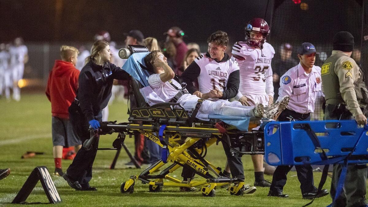 Laguna Beach High receiver Jack Crawford is wheeled off the field by medics after dislocating his jaw in the first quarter of a CIF Southern Section Division 12 semifinal game at Lakewood Artesia on Friday.