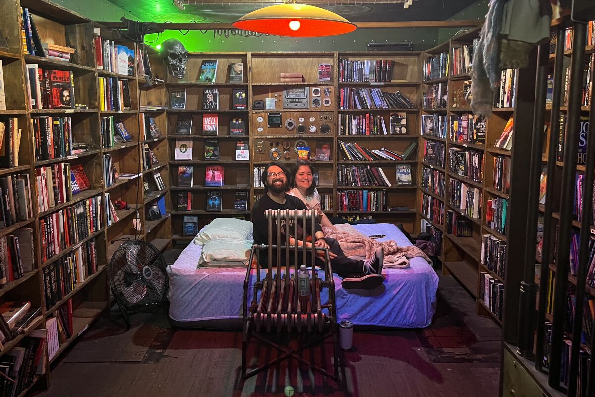 A couple set up their air mattress amid shelves of books.