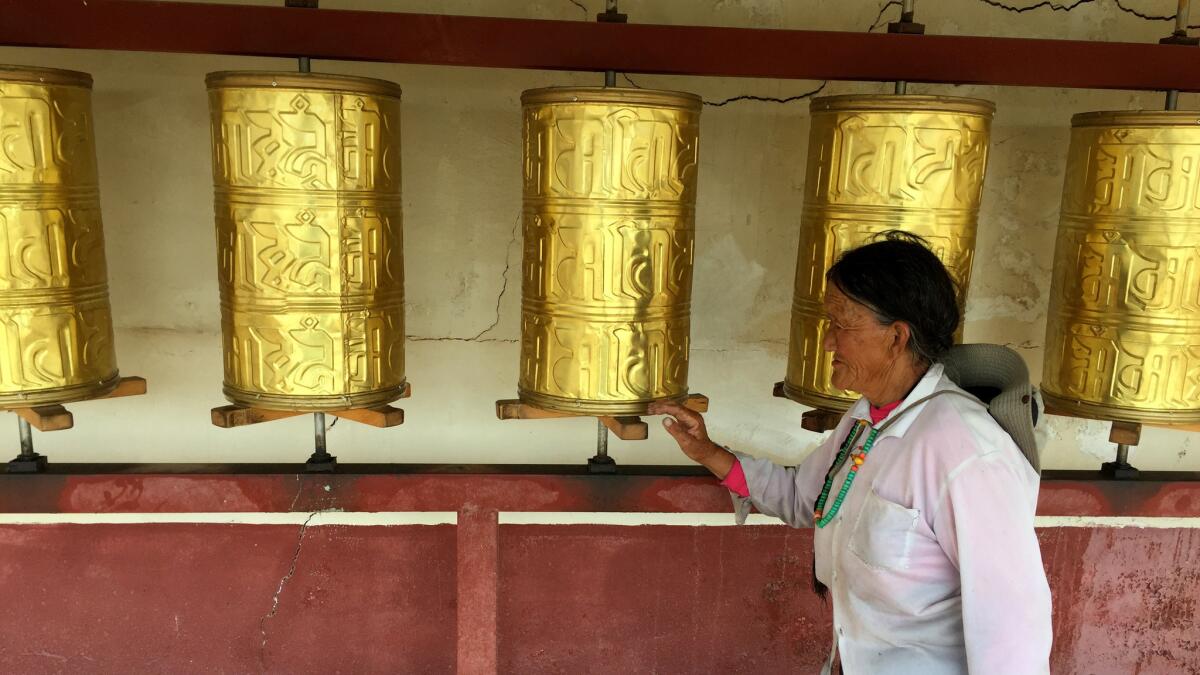 A Tibetan woman spins prayer wheels at a roadside tourist attraction in Aba prefecture. (Jonathan Kaiman / Los Angeles Times)