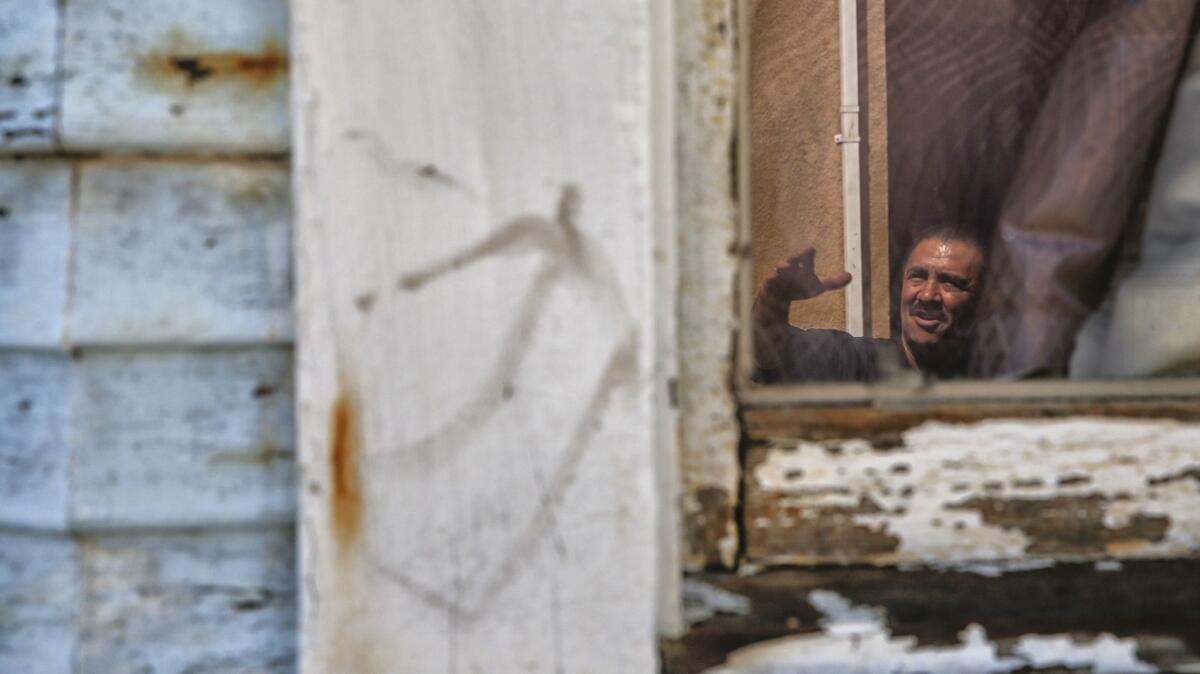 Paint peels from the Boyle Heights home of Ramon Tenorio, reflected in his kitchen window in June. In the designated soil cleanup zone near the Exide battery-recycling plant, residents now are facing the risk of recontamination from lead paint.