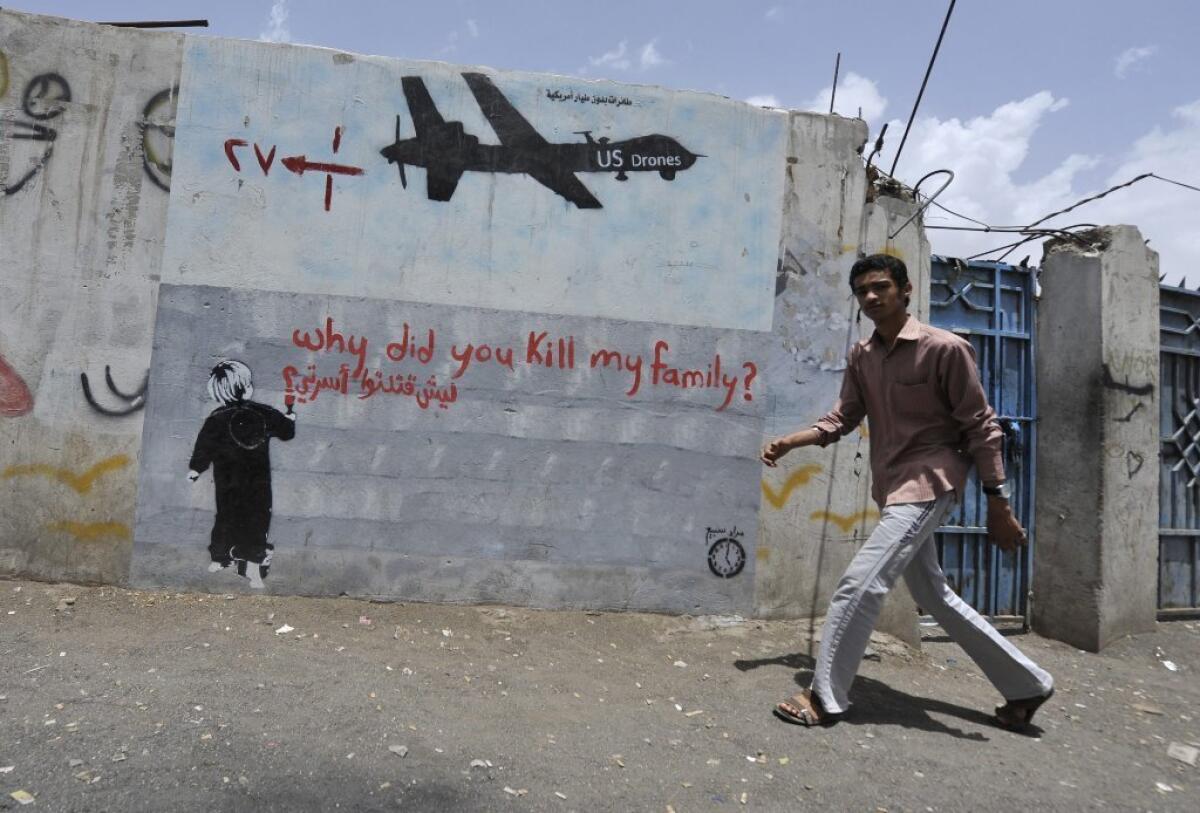 A man walks near graffiti protesting U.S. drone operations in Yemen last April.