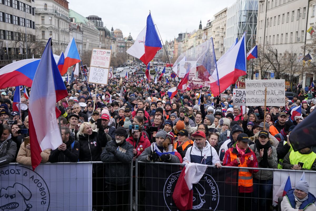 People wave flags and banners as they gather to protest against the governments restrictions to curb the spread of COVID-19 in Prague, Czech Republic, Sunday, Jan. 9, 2022. (AP Photo/Petr David Josek)