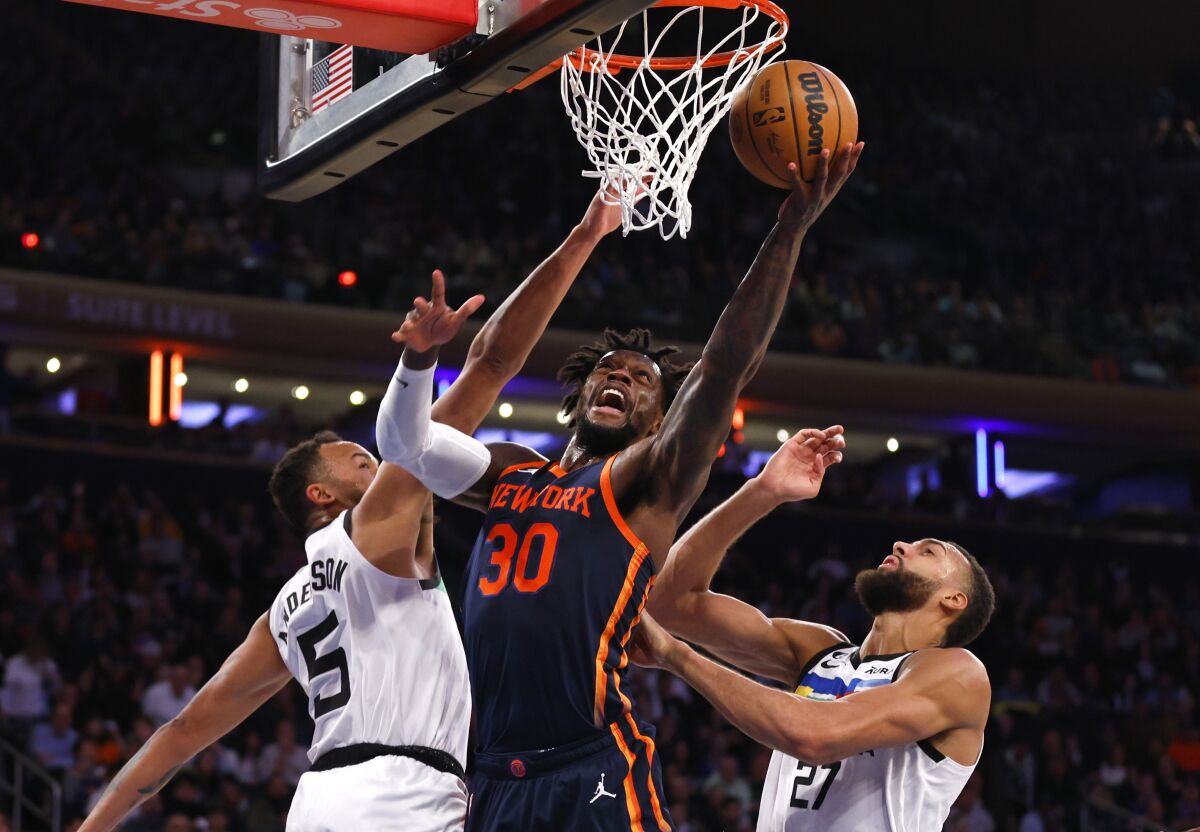 New York Knicks forward Julius Randle (30) drives to the basket against Minnesota Timberwolves forward Kyle Anderson (5) and center Rudy Gobert (27) during the second half of an NBA basketball game, Monday, March 20, 2023, in New York. (AP Photo/Noah K. Murray)
